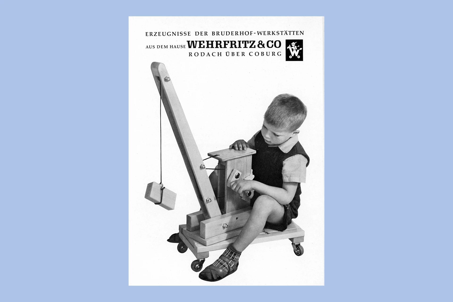 Katalog-Titelseite der Firma Wehrfritz mit einem Foto von einem Kind, das mit einem hölzernen Spielkran spielt; Schwarz-Weiß-Foto.
