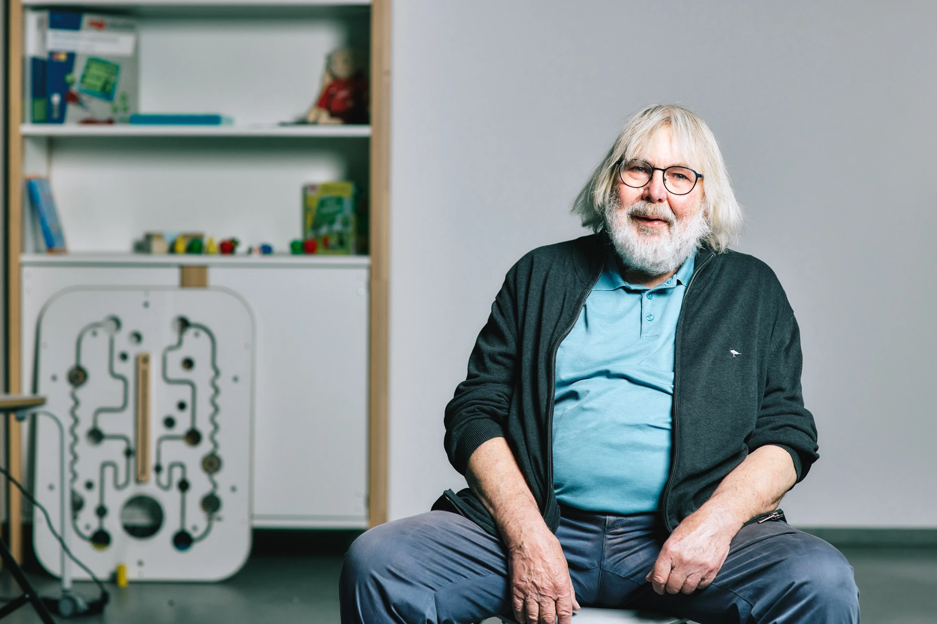 Horst Dwinger, der ehemalige Design-Chef von Wehrfritz, sitzt auf einem Stuhl, im Hintergrund Spielzeug.