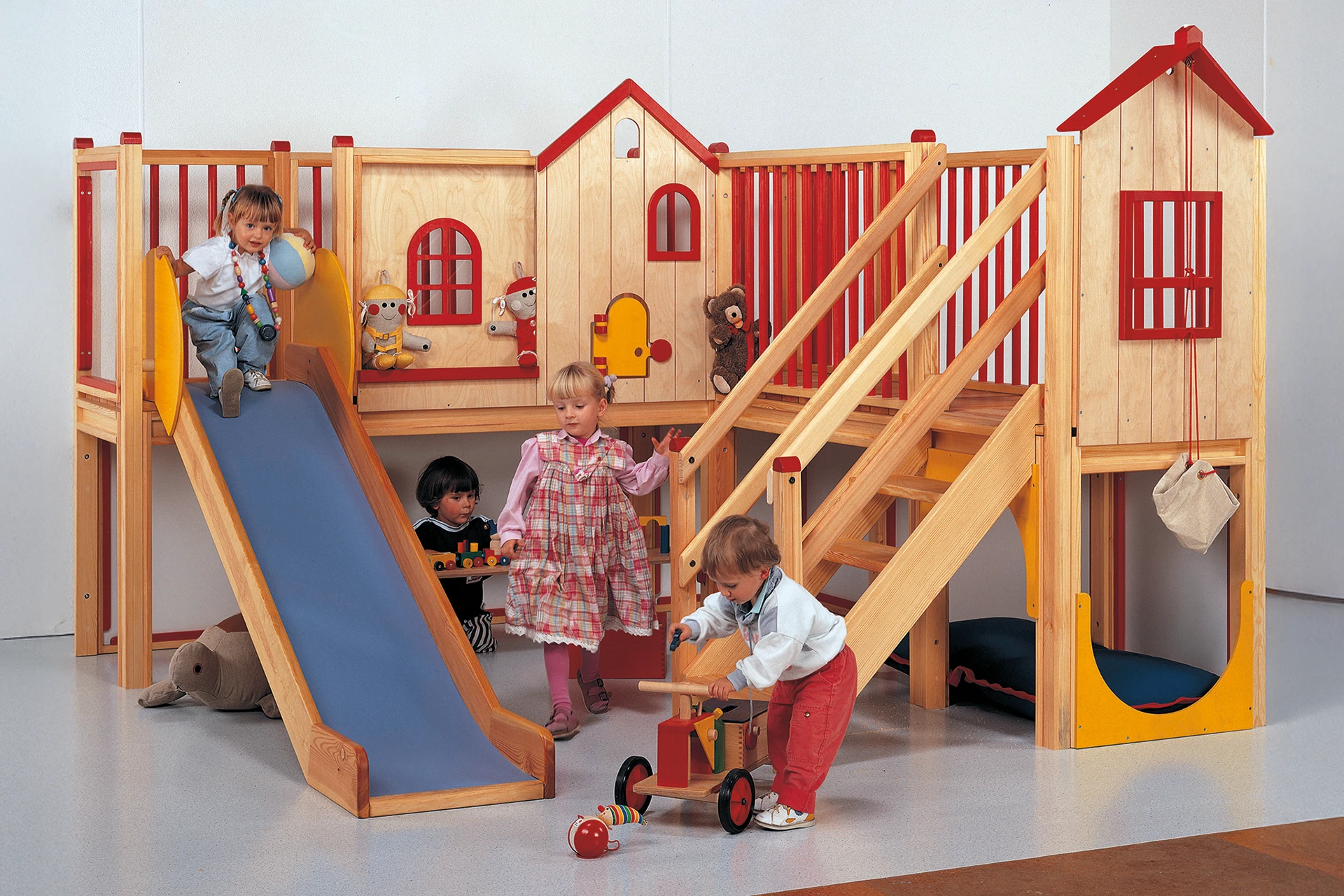 Kinder spielen mit dem zweistöckigen Möbelstück Gemino mit Rutsche der Firma Wehrfritz.