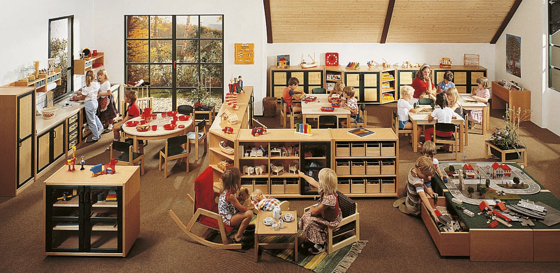 Kinder spielen in einem Kindergartenraum, der mit Raumteilern ausgestattet ist.