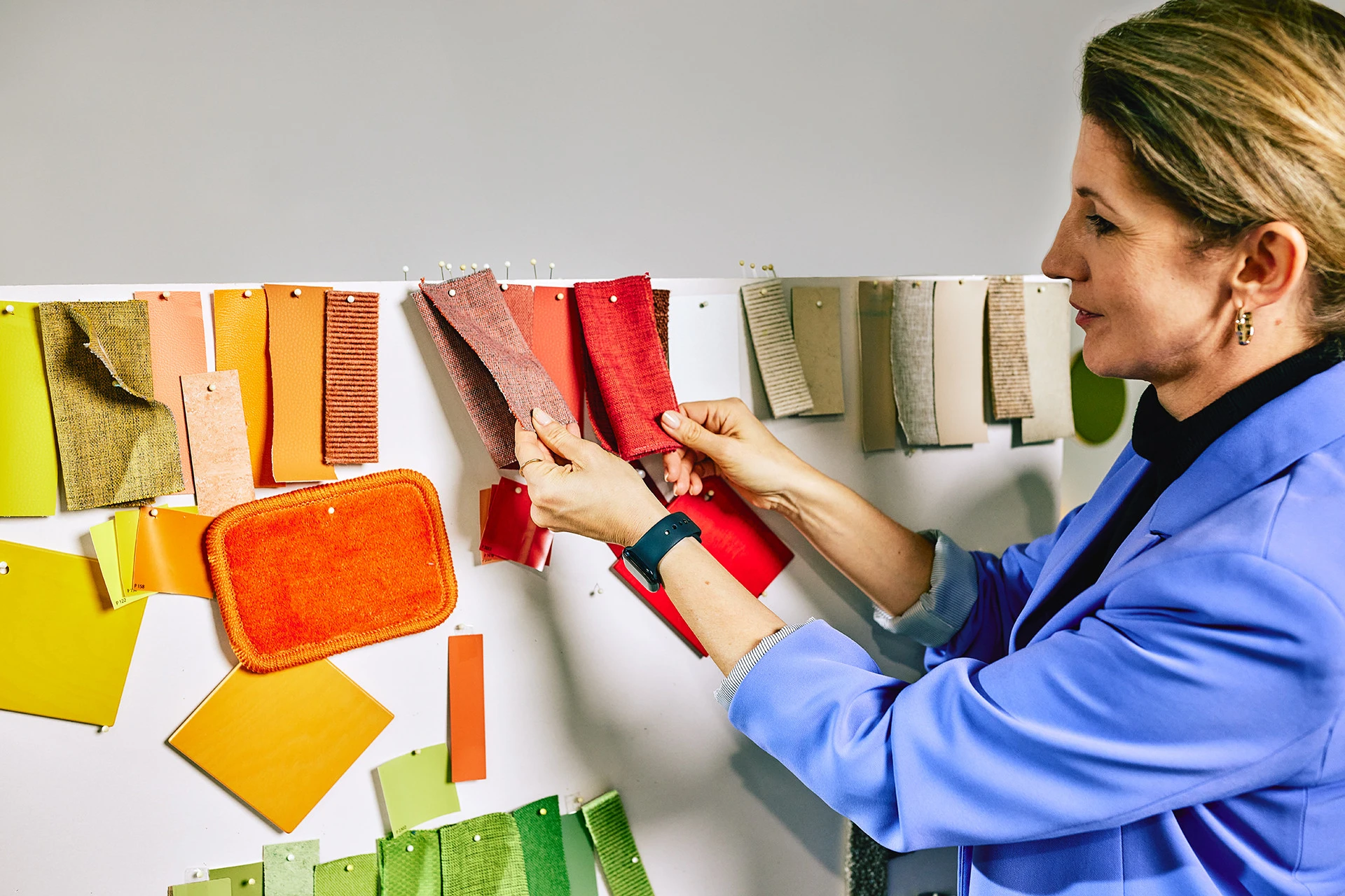 Produktmanagerin Lisa Werner befühlt verschiedenfarbige Stoffmuster, die an einer Wand hängen.