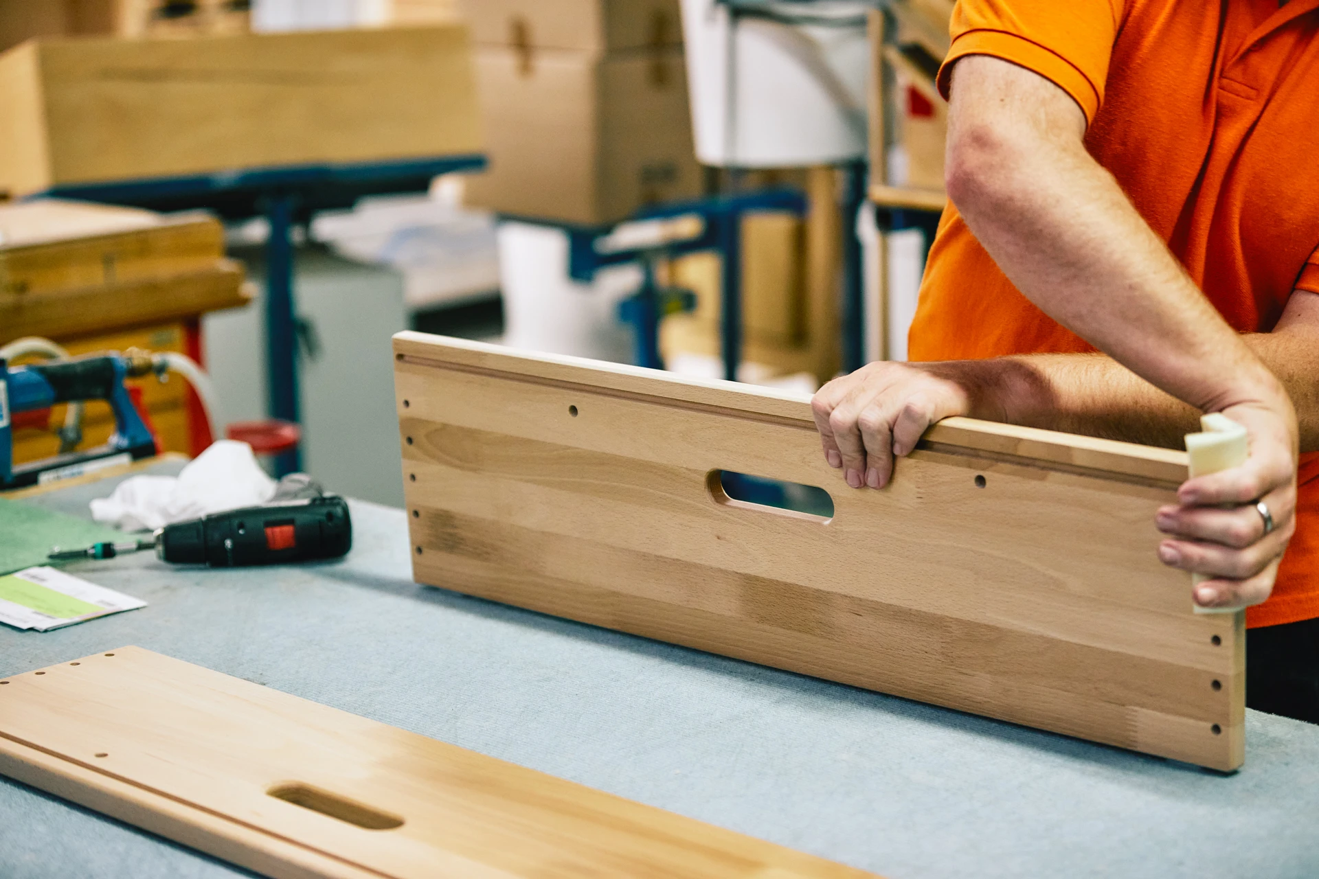 Ein Schreiner schleift ein Holzelement eines Möbelstücks.