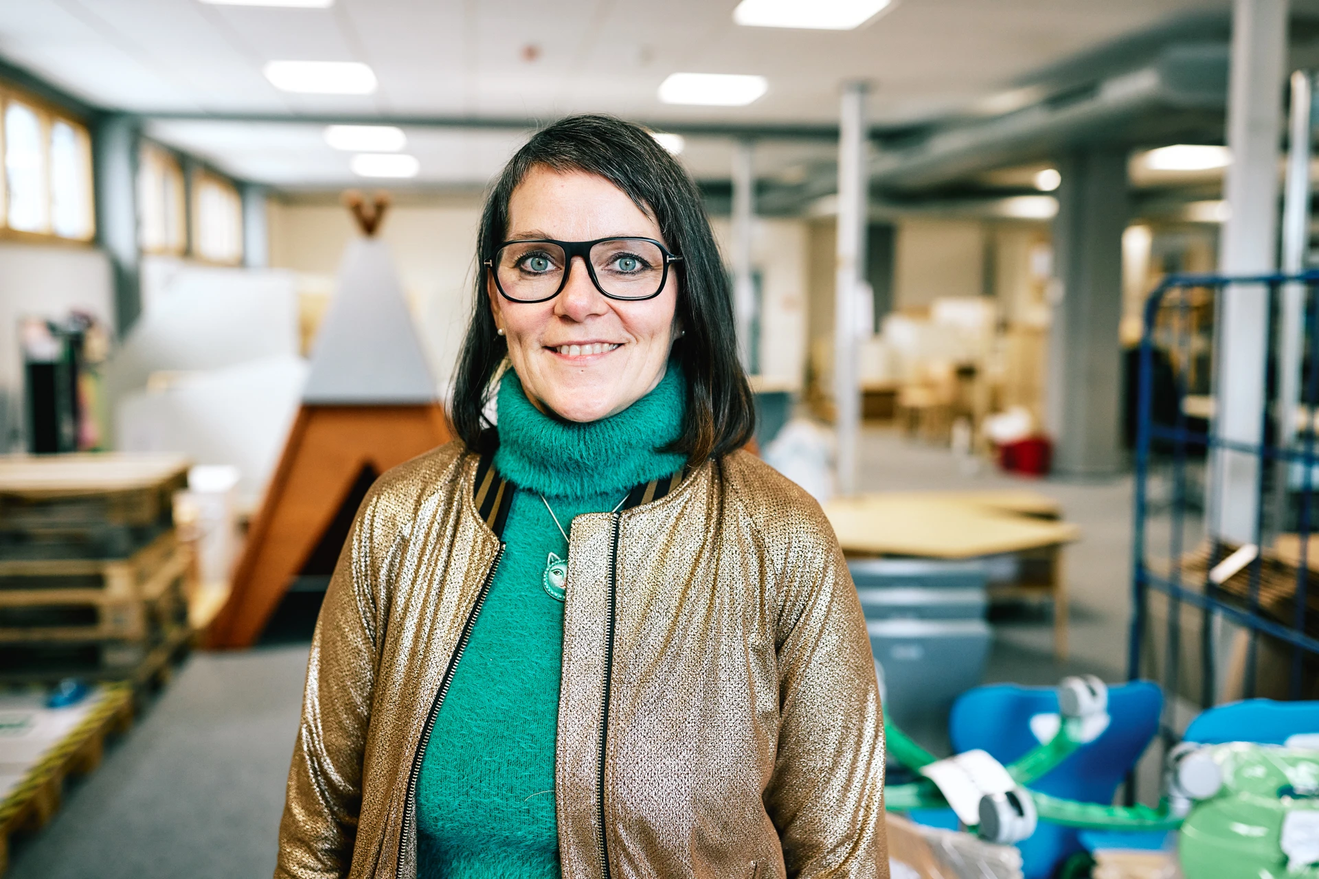 Portraitfoto von Maria Pfefferlein. Sie hat braune Haare, trägt eine Brille und einen grünen Pullover.