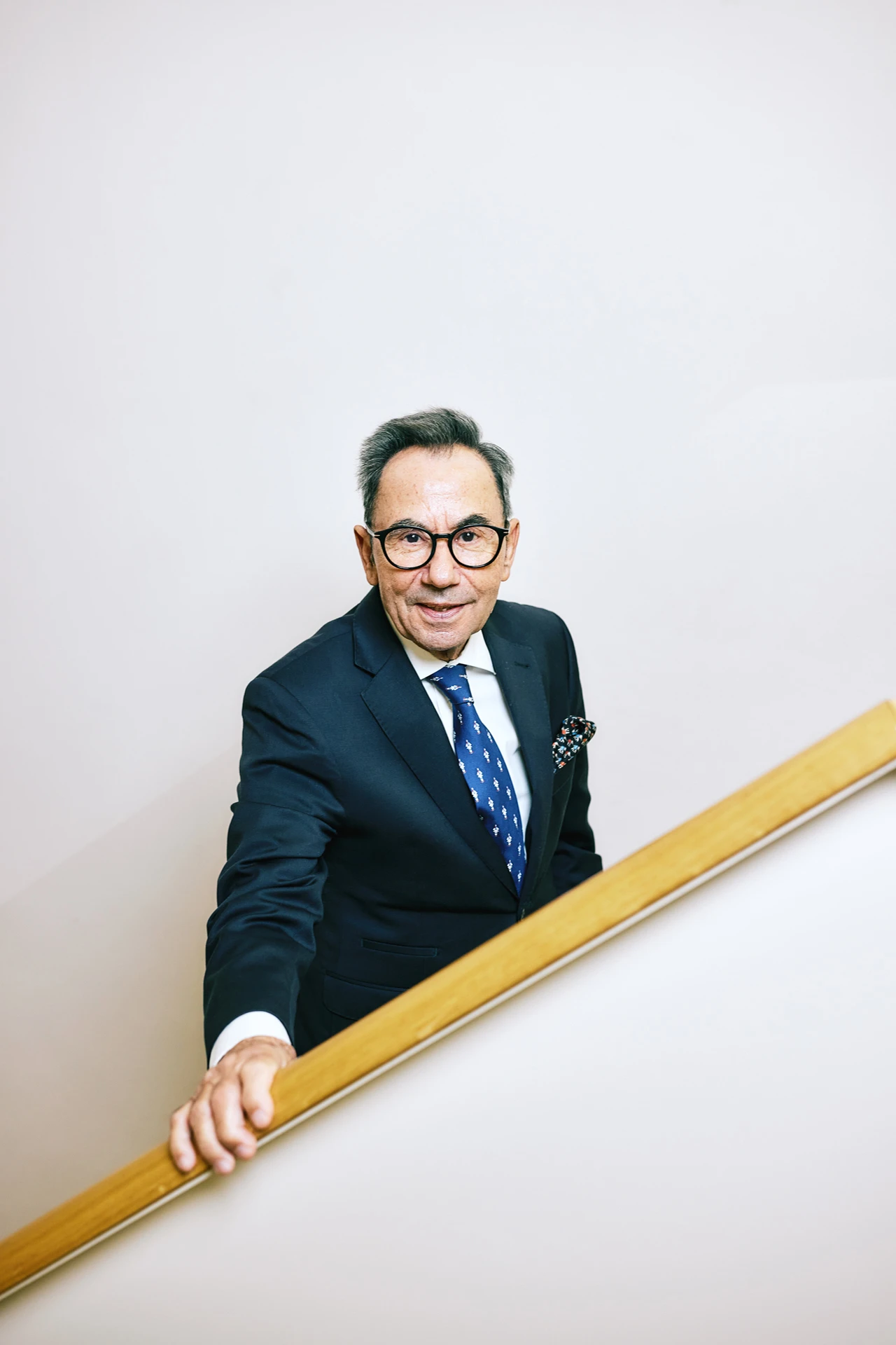 Portraitfoto von Prof. Dr. mult. Wassilios E. Fthenakis. Er steht in einem Treppenhaus und trägt einen Anzug.