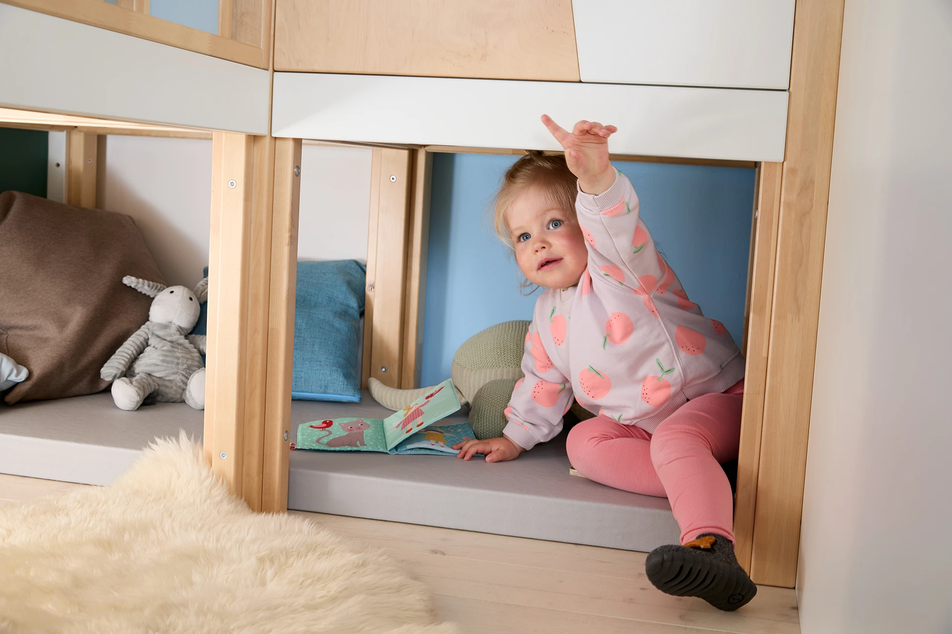 Ein Kind sitzt in der unteren Ebene des Möbelstücks Gemino wie in einer Höhle.
